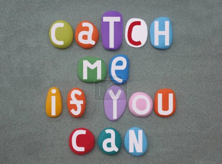 Catch me if you can, creative slogan composed with hand painted multi colored stone letters over green sand