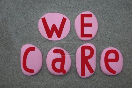 We care, creative slogan composed with pink and red colored stone letters over green sand