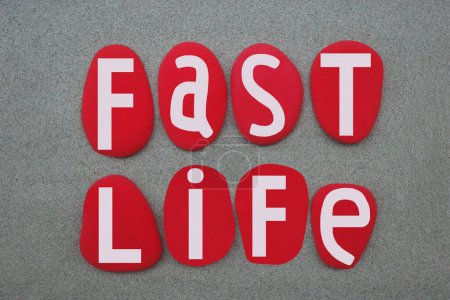 Fast life, creative slogan composed with hand painted red colored stone letters over green sand