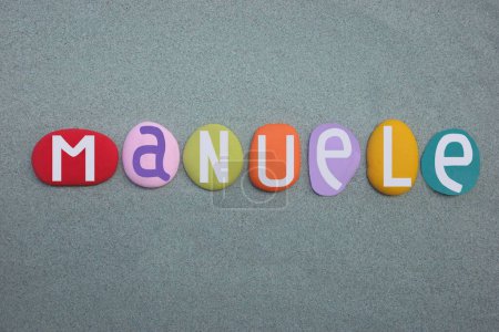Manuele, masculine given name composed with multi colored stone letters over green sand