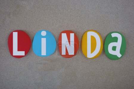 Linda, nombre de pila femenino compuesto por letras de piedra multicolor pintadas a mano sobre arena de playa