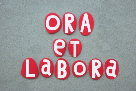 Ora et labora, latin phrase meaning pray and work, refer to the monastic practice of working and praying, generally associated with its use in the Rule of Saint Benedict, creative text composed with red colored stone letters over green sand