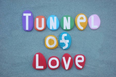 Tunnel of love, creative slogan composed with hand painted multi colored stone letters over green sand