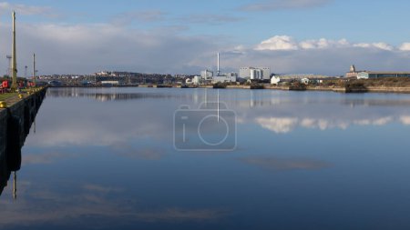 Blick über den Eingangskanal der Barry Docks in Südwales. Das Barry Biomass Renewable Energy Plant spiegelt sich im Wasser und die Stadt ist in der Ferne zu sehen