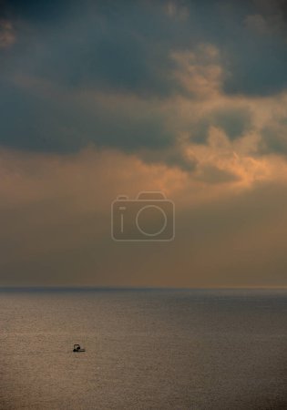 Photo for Sunrise in the sea with cloud stormy clouds and orange colour. Seascape in the morning. Sun rays in the ocean. Fishing boat sailing - Royalty Free Image