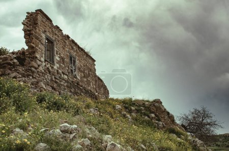 Téléchargez les photos : Abaissement du mur de briques endommagé. Maison abandonnée abandonnée contre un ciel nuageux. - en image libre de droit