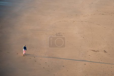 Téléchargez les photos : Personne non reconnue marchant sur la plage de sable au coucher du soleil. Mode de vie sain. Faire de l'exercice à l'extérieur. Ballybunion plage Irlande - en image libre de droit
