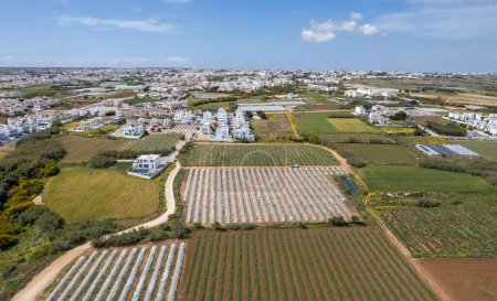 Aerial drone view of greenhouses in a row, covered with a transparent film of growing vegetables and fruits. Food cultivation Farming, bio products. Paralimni Cyprus