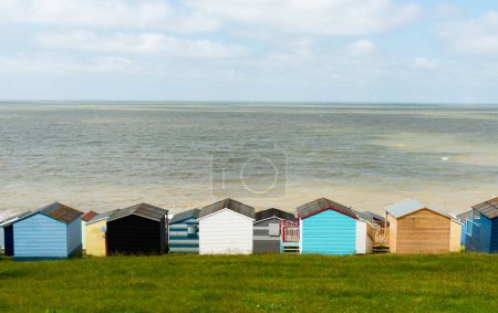 Coloridas cabañas de playa de vacaciones casas frente al mar azul tranquilo. Whitstable, Kent Sureste de Inglaterra