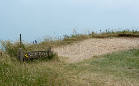 Cliff edge warning sign. Caution crumbling slope. Risk of injury or death. Danger crag notice sign.