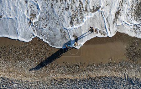 Photo for Aerial drone point of view of person walking on sand in a beach. Stormy waves idyllic beach in winter. - Royalty Free Image