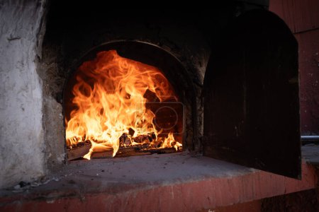 Fire and burn coals in stone oven. Oven made of bricks and clay. Clay oven for cooking food and pizza.