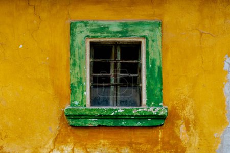 Téléchargez les photos : Photo de façade de vieille maison avec fenêtre verte et mur jaune. - en image libre de droit