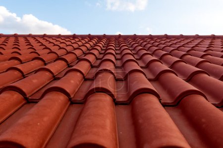 Foto de Techo de teja roja bajo cielo azul. Una parte es un techo y la otra es un cielo azul puro. - Imagen libre de derechos