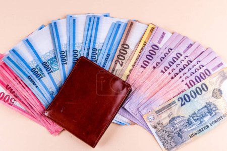 Billetes HUF húngaros extendidos y billetera de cuero sobre fondo amarillo