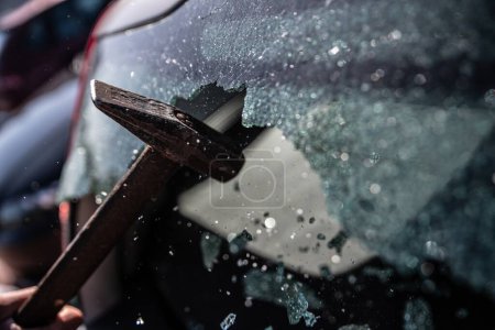 Foto de Ladrón de coches rompe la ventana del coche con un martillo - Imagen libre de derechos
