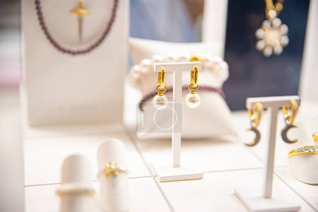 Foto de Pendientes de perlas de lujo exhibidos en medio de una variedad de joyas elegantes en una pantalla brillante - Imagen libre de derechos