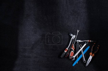 Foto de Colección de varias herramientas de mano dispuestas sobre una superficie de textura oscura, incluyendo llaves, alicates, destornilladores y un martillo - Imagen libre de derechos