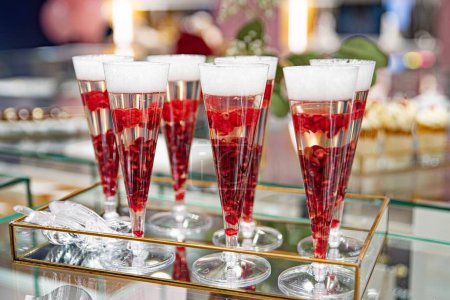 Foto de Set de flautas de champán rellenas de una bebida roja burbujeante y adornadas con bayas rojas. - Imagen libre de derechos