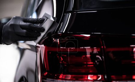 Foto de Detallador experto aplica los toques finales a un coche brillante capa con precisión. - Imagen libre de derechos