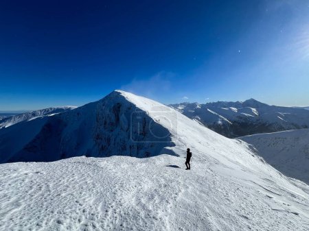 Foto de Senderistas viaje de invierno a través de las crestas nevadas de los Tatras polacos bajo el cielo despejado. - Imagen libre de derechos