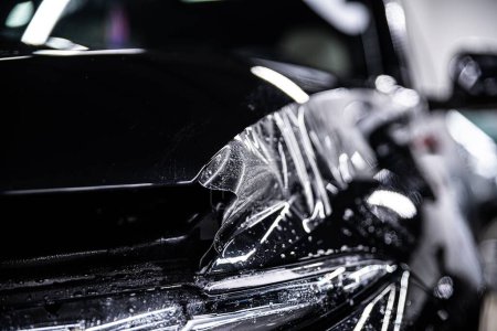 Téléchargez les photos : Voiture noire protégée avec PPF Paint Protection Film dans une voiture détaillant studio - en image libre de droit