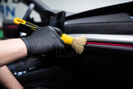 Foto de Lavado de coches o coche detalle trabajador del estudio cuidadosamente limpieza interior del coche con cepillo especial - Imagen libre de derechos