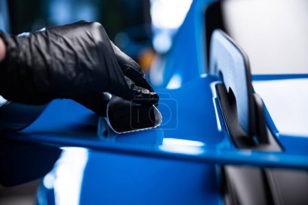 Foto de Coche efectivo o coche detallando trabajador de estudio aplicando grafeno o recubrimiento de cerámica en coche deportivo azul. - Imagen libre de derechos