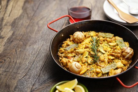 Photo for Spanish Valencian traditional paella; rabbit, chicken, garrofon beans, snails, Moroccan green beans, saffron, and bomba rice. - Royalty Free Image