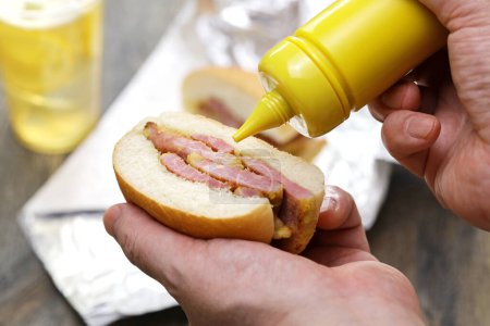 Poner mostaza en un sándwich de tocino peameal.Plato distintivo de Toronto