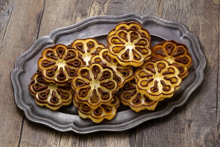 Téléchargez les photos : Biscuits à la rosette trempés au chocolat (fleur de rose) sur une assiette en étain - en image libre de droit