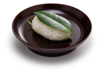 Téléchargez les photos : Tsubaki Mochi est le plus vieux sucré du Japon. Un gâteau de riz gluant rempli de pâte de haricot sucrée est pris en sandwich entre deux feuilles de camélia fraîches. - en image libre de droit