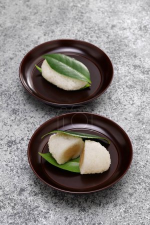 Téléchargez les photos : Tsubaki Mochi est le plus vieux sucré du Japon. Un gâteau de riz gluant rempli de pâte de haricot sucrée est pris en sandwich entre deux feuilles de camélia fraîches. - en image libre de droit