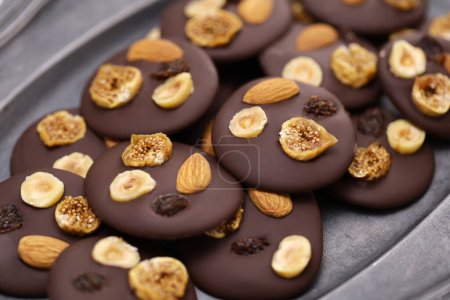 Photo for Homemade chocolate mendiants with traditional toppings; almonds, raisins, hazelnuts, fig.   French Christmas sweets. - Royalty Free Image