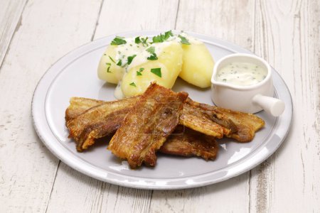 Téléchargez les photos : "Stegt flsk med persillesovs "(panse de porc tranchée avec peau sur et frit, servi avec de la sauce au persil et pommes de terre bouillies). Alimentation nationale du Danemark. - en image libre de droit