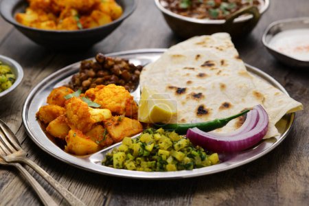 Foto de Placa vegetariana estilo indio. kala chana masala, aloo gobi ki sabzi, mooli ki sabzi y chapati. - Imagen libre de derechos