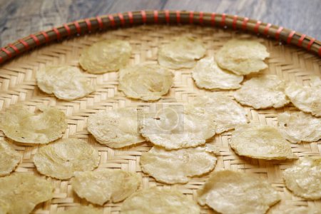 Téléchargez les photos : Des craquelins indonésiens vides faits de noix de Belinjo écrasées. Séchage sur un plateau en bambou. - en image libre de droit