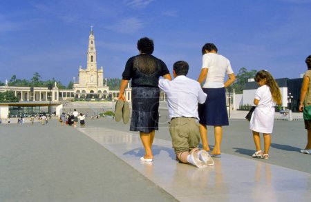 Téléchargez les photos : Fatima, Portugal - 12 mai 2019 : Sanctuaire de Fatima. Le pèlerin accomplit sa pénitence et / ou sa promesse à genoux le long de l'aire de prière à la Chapelle des Apparitions. - en image libre de droit