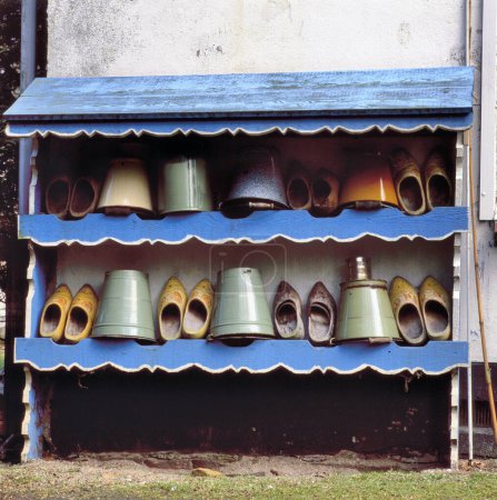 Photo for Typical Dutch image of empty containers and wooden shoes under a tiled roof at a farm - Royalty Free Image