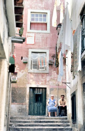 Foto de LISBOA, PORTUGAL- 09 AGOSTO 2017: Pareja de ancianos sentada frente a su casa en la zona de Alfama - Imagen libre de derechos