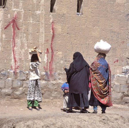 Téléchargez les photos : Des femmes voilées se parlent dans une rue de Sanaa, la capitale du Yémen - en image libre de droit