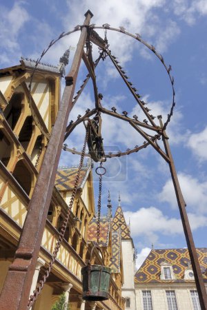BEAUNE, FRANCE- MAY,13,2024: At foreground the water well of Hotel Dieu or Hospice de Beaune, in Burgundy region, France