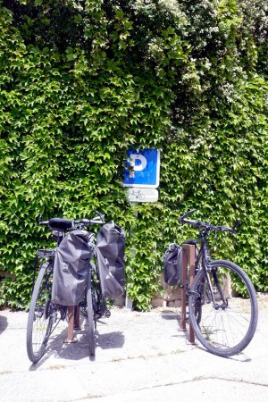 Two bikes parked under a French road sign: parking for bicycles only in the city of Apt, France               