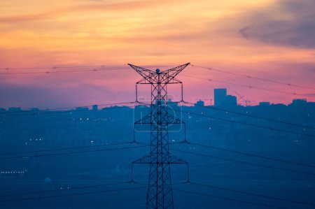 Electricity high voltage tower in a city during sunset