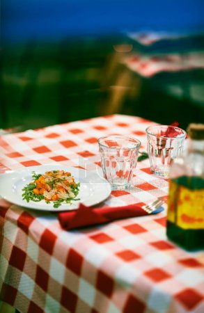 Téléchargez les photos : Gnocchi à la pomodoro (sauce tomate) et salade de roquette au parmesan sur une table d'une typique Trattoria italienne. - en image libre de droit