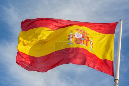 Photo for Flag of Spain, called La Rojigualda, waving on a blue sky. - Royalty Free Image