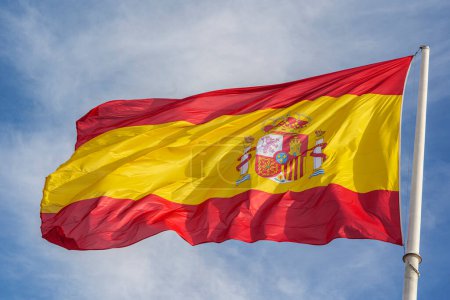 Photo for Flag of Spain, called La Rojigualda, waving on a blue sky. - Royalty Free Image
