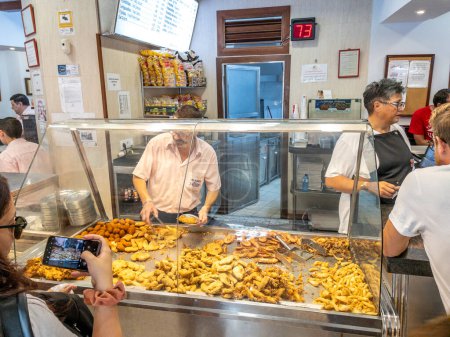 Photo for Cadiz, Spain - August 1, 2023. Waiter serving Pescito Frito (Assortment of Fried Fish) in a tipycal spanish Freiduria (Fry Shop). Cadiz, Andalusia, Spain. - Royalty Free Image