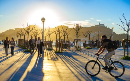 Photo for San Sebastian, Spain - March 13, 2024. People enjoying a sunset crossing La Concha Promenade at the level of the Don Quijote y Sancho Panza square. San Sebastian (Donostia), Basque Country, Gipuzkoa. Spain. - Royalty Free Image