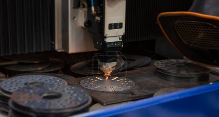 Foto de Máquina de corte por láser CNC que corta agujeros en la pieza de trabajo de metal en fábrica. Fabricación industrial. - Imagen libre de derechos
